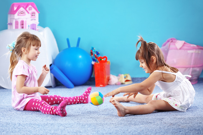 Bambine che giocano sul pavimento della camera da letto